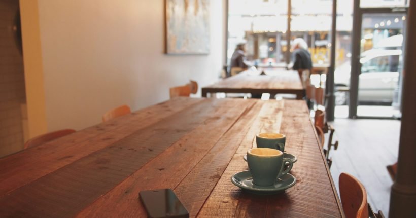 two gray ceramic mugs on brown wooden dining table
