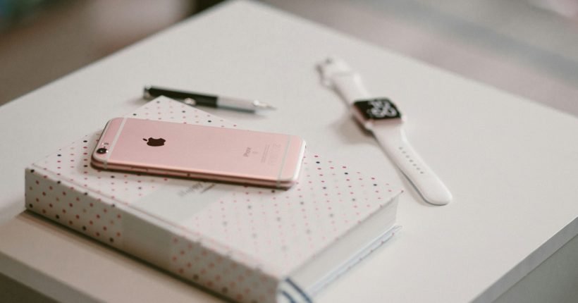 rose gold iPhone 6s on book near Apple watch