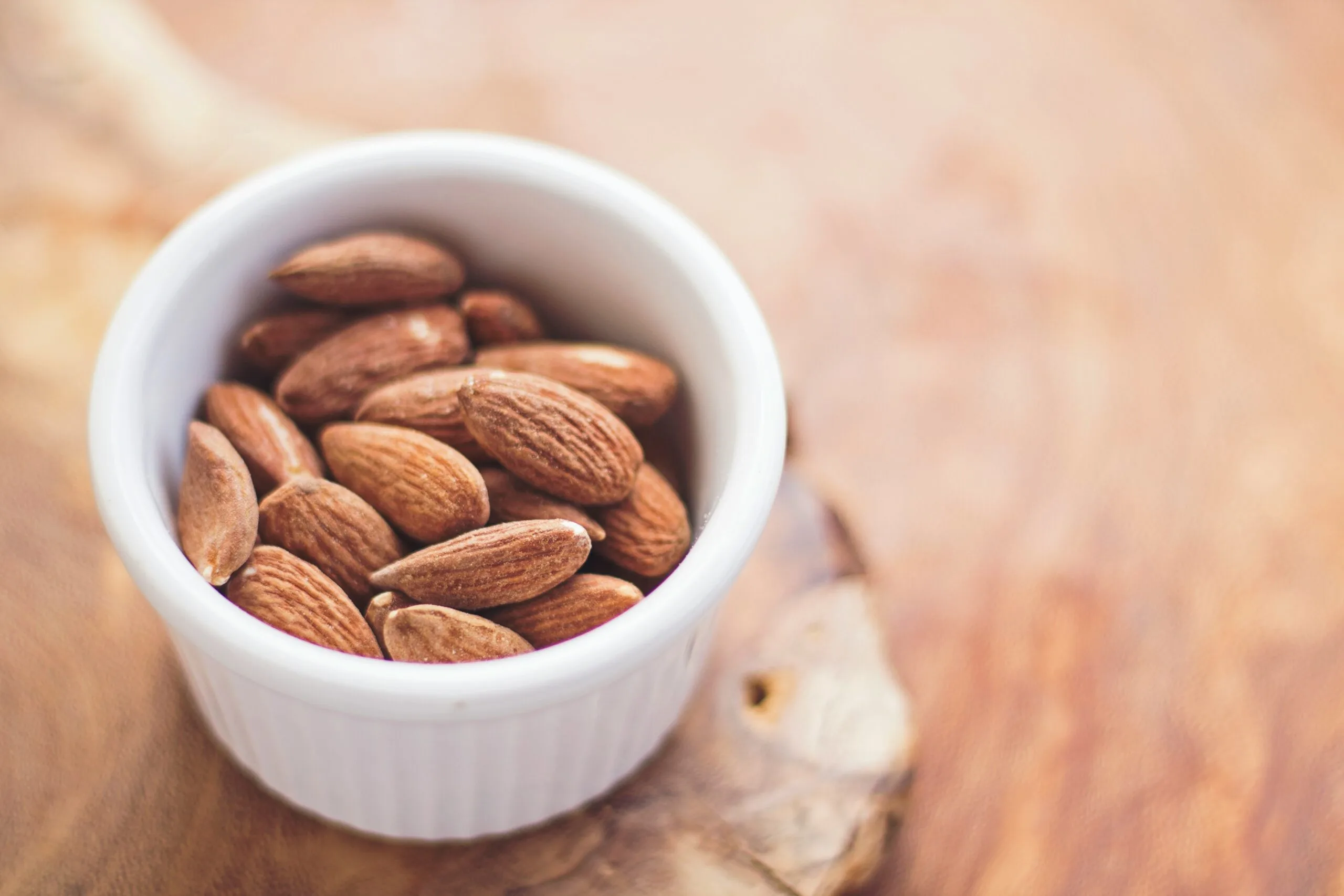 shallow focus photography of almonds (amêndoas) in white ceramic bowl